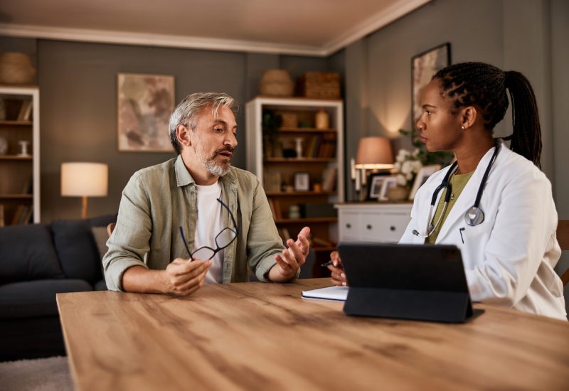 A senior man talking with a therapist during a visit.